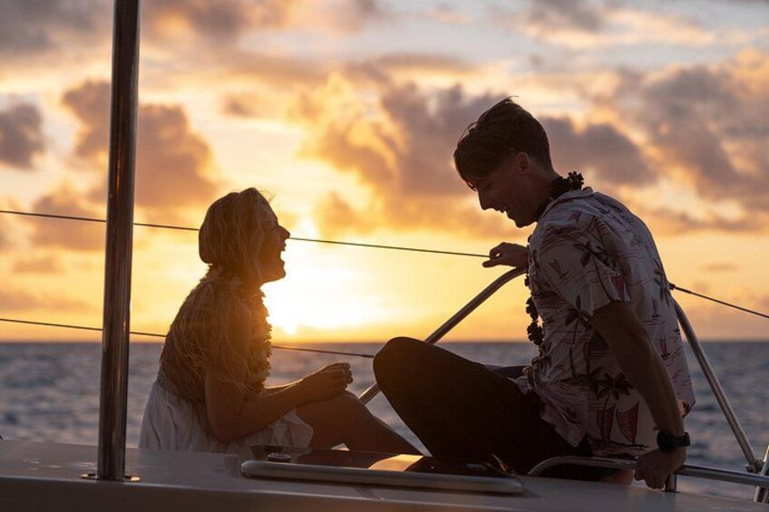 Two people sitting on a boat with a sunset in the background. 2