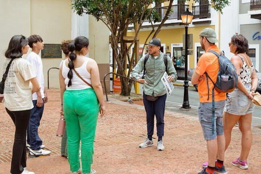 A group of people standing on a paved area with a building in the background. 1