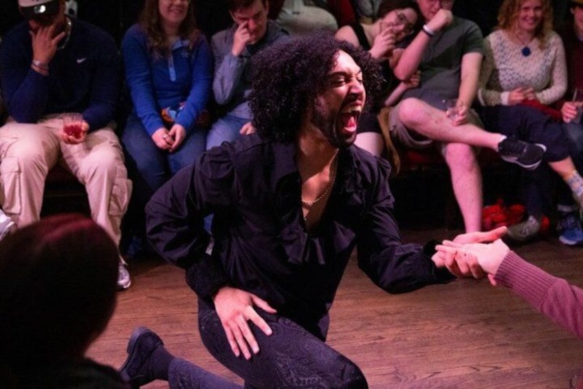 A person in a black shirt kneeling on a wooden floor, reaching out to another person. 4