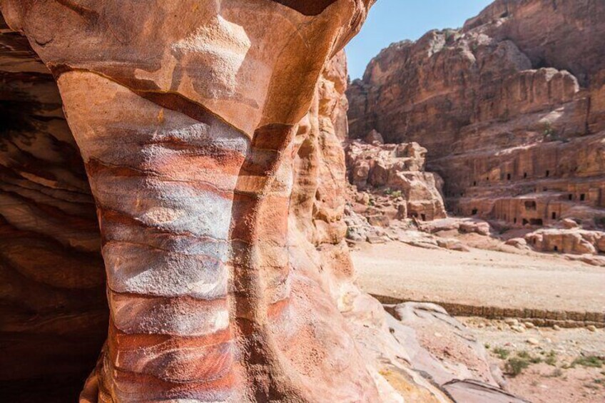 A large rock formation with layered strata and ancient ruins in the background. 4