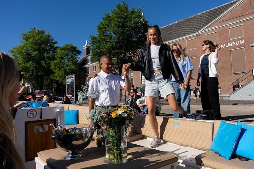 A person walking on a sidewalk, a building labeled 'MUSEUM' in the background, and a table with a vase of flowers. 5