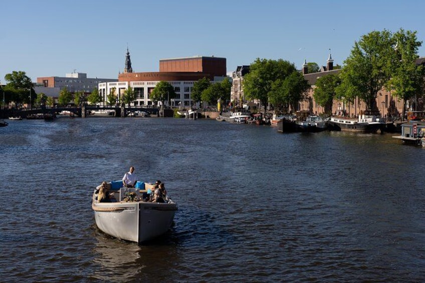A boat on a river with buildings and trees in the background. 4