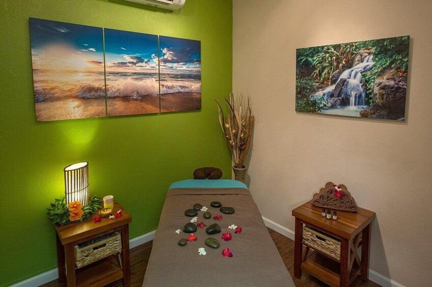A room with a massage table, a green wall, and two paintings. 1