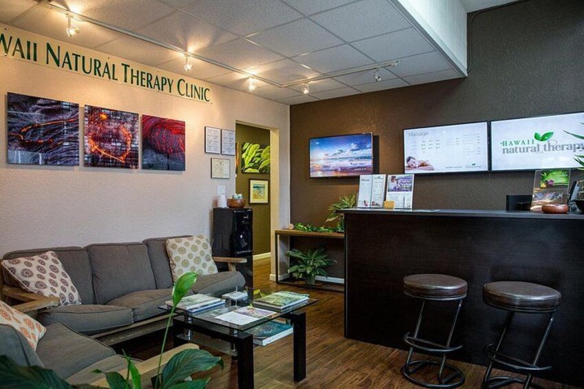 A clinic interior with a reception desk, bar stools, a sofa, and wall art. 2