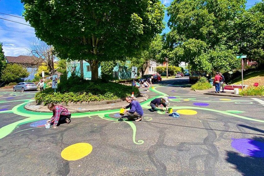 Children painting on a street, with trees and houses in the background. 2