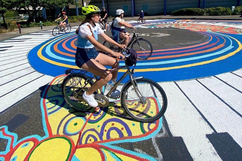 People riding bicycles on a colorful painted surface with concentric circles. 4