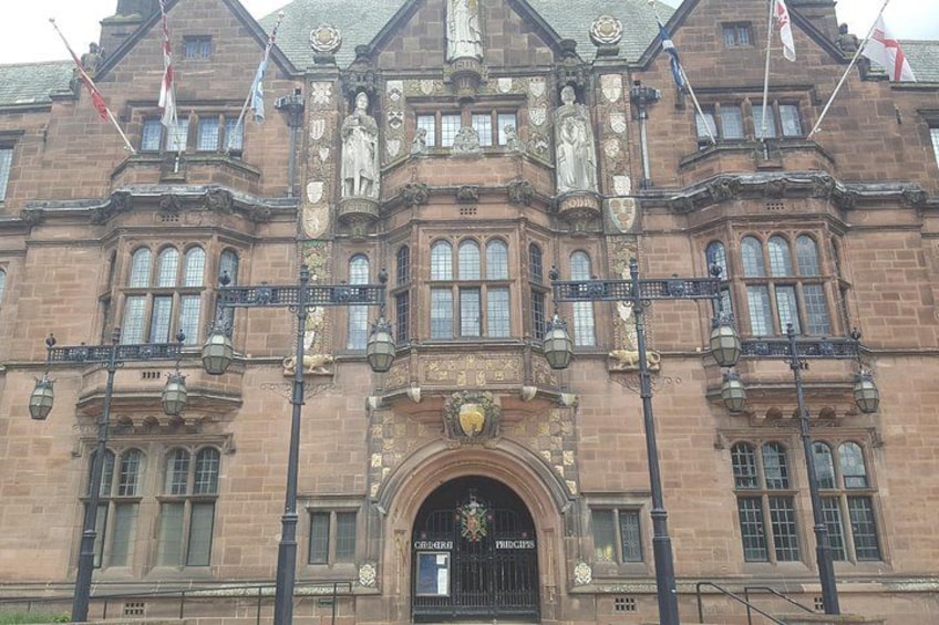 A historic building with ornate architecture, including a large arched entrance and multiple flags. 3