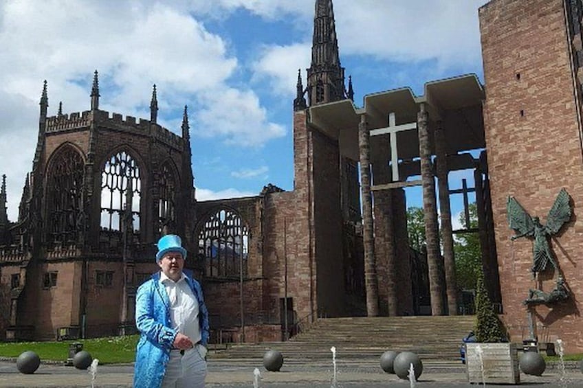 A person in a blue jacket and hat standing in front of a Gothic-style church with a large cross and pointed spires. 2