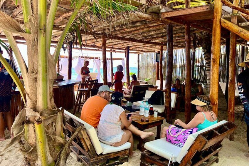 A beachside restaurant with wooden furniture and a thatched roof. 3