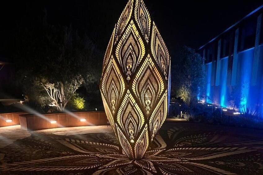 A large, illuminated geometric sculpture in an outdoor setting at night. 4