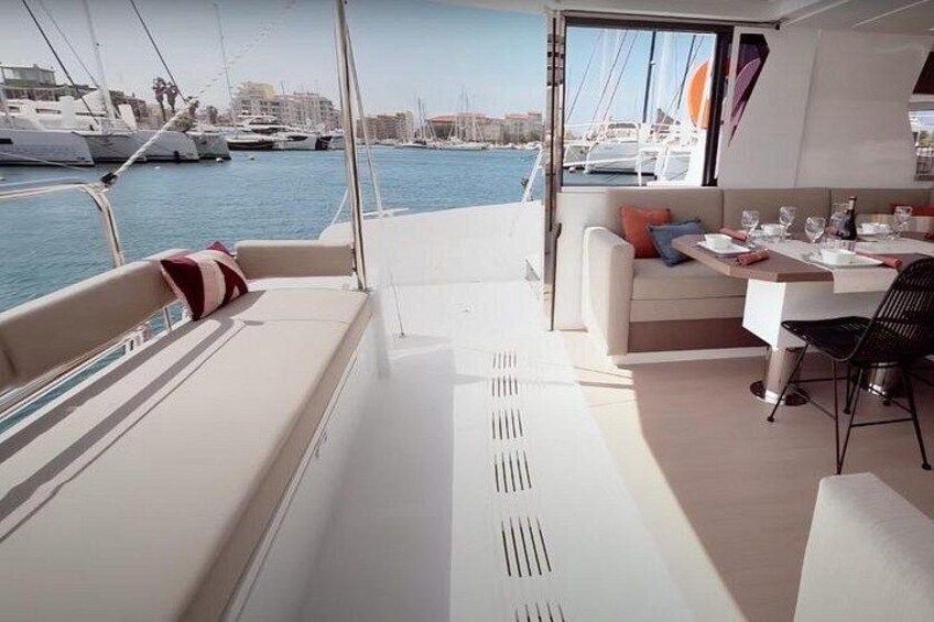 A yacht interior with a dining area, a sofa, and a view of the marina. 4