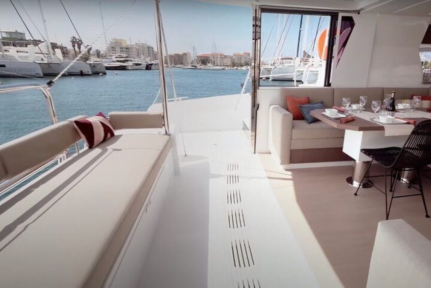 A yacht interior with a dining area, a sofa, and a view of the marina. 2