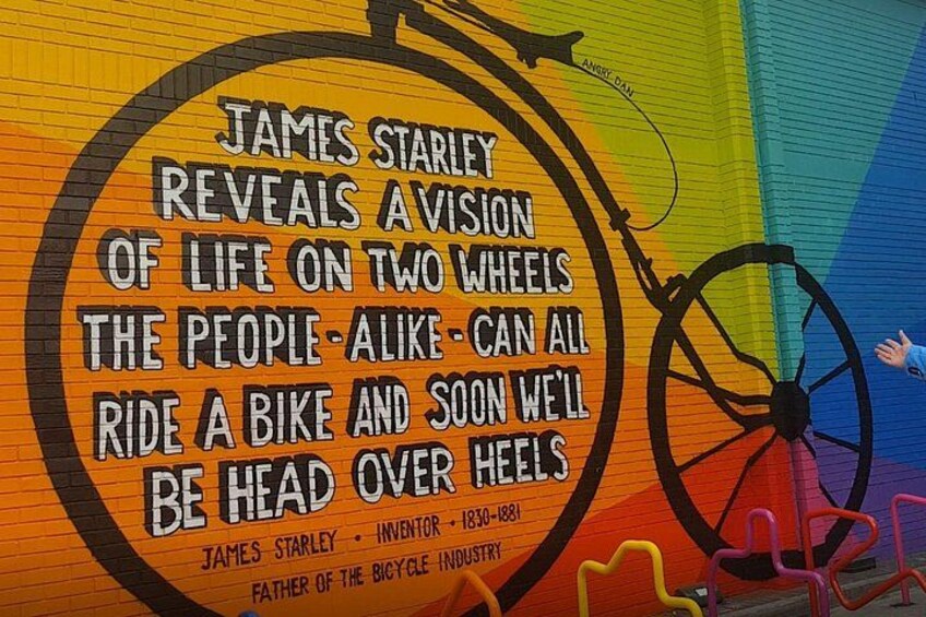 A colorful mural with a bicycle wheel and text about James Starley. 1