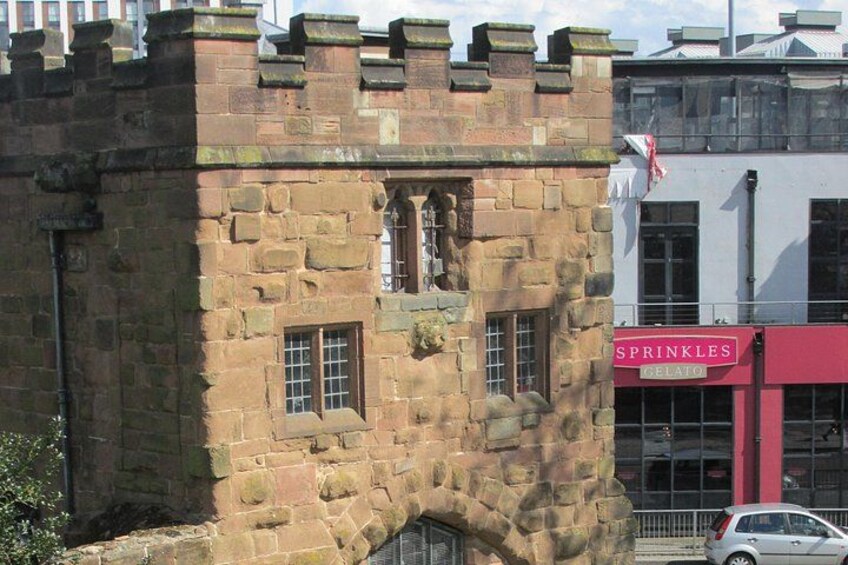 A stone building with a castle-like facade, a flag, and a Sprinkles Gelato shop in the background. 3