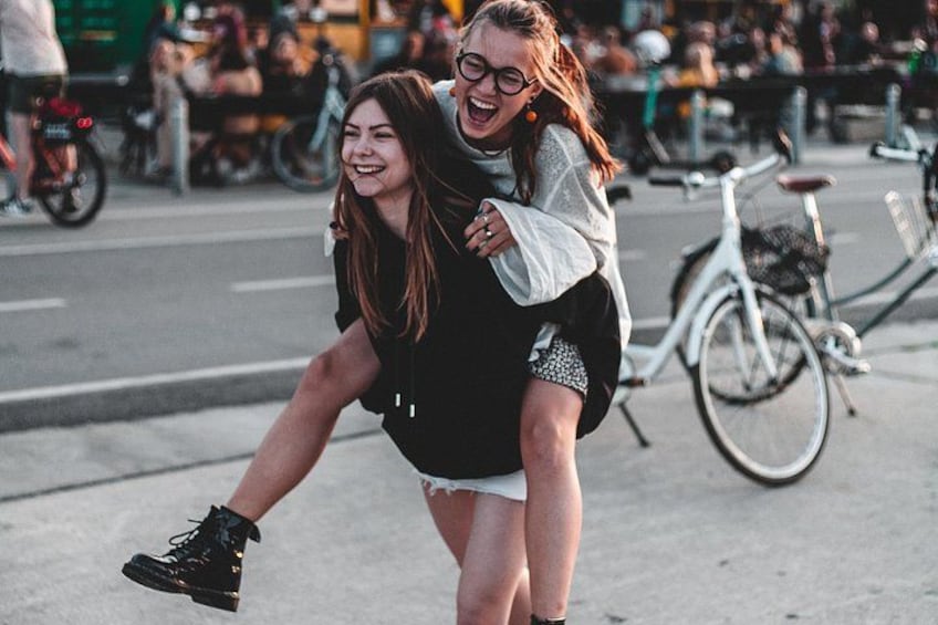 Due persone in sella a una bicicletta, con una folla e una bicicletta bianca sullo sfondo. 4