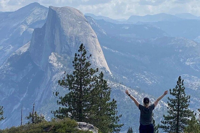 A person standing with arms raised, overlooking a mountain landscape with a prominent peak. 5
