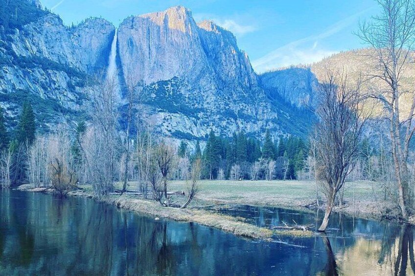A river reflecting mountains, trees, and a clear sky. 3