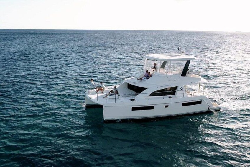 Eine weiße Yacht auf ruhigem, blauem Wasser, Personen befinden sich auf dem Deck. 1