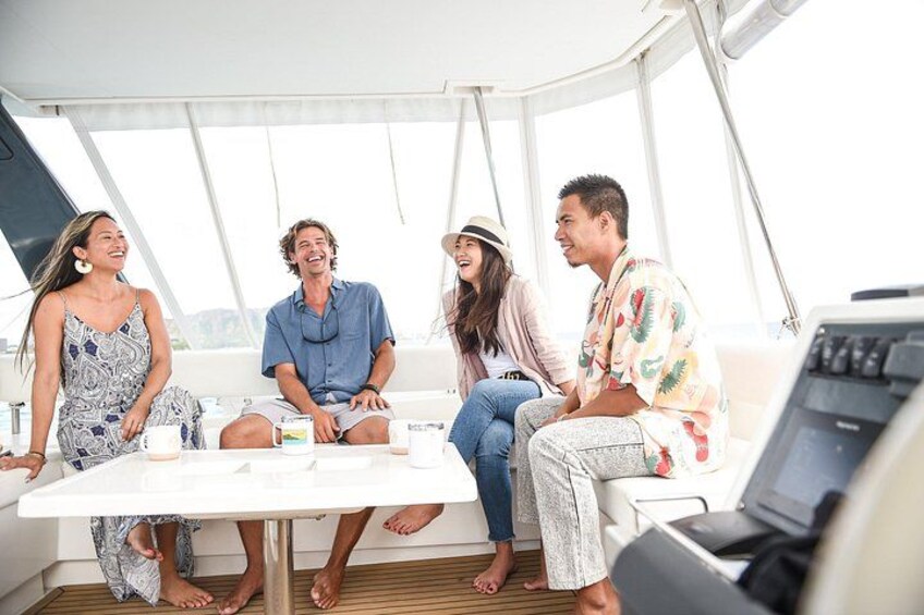 Eine Gruppe von Menschen sitzt auf dem Bootsdeck und unterhält sich. 2