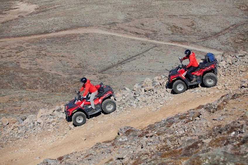 Two people riding ATVs on a rocky terrain. 2