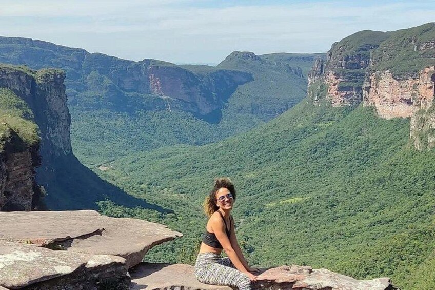 A person sitting on a rock with a mountainous landscape in the background. 4