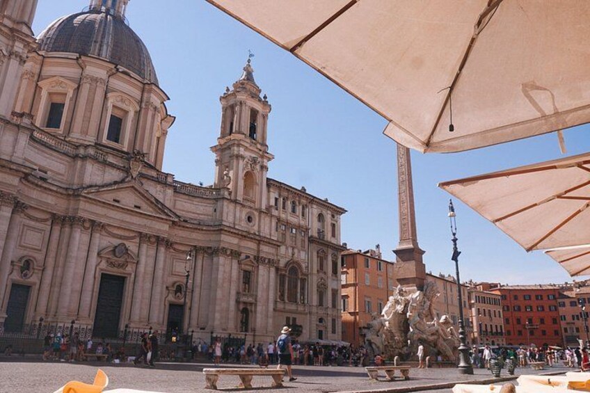 A historic building with a dome and bell tower, surrounded by people and outdoor seating. 3
