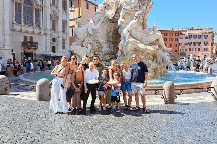 A group of people posing in front of a large fountain with statues. 4