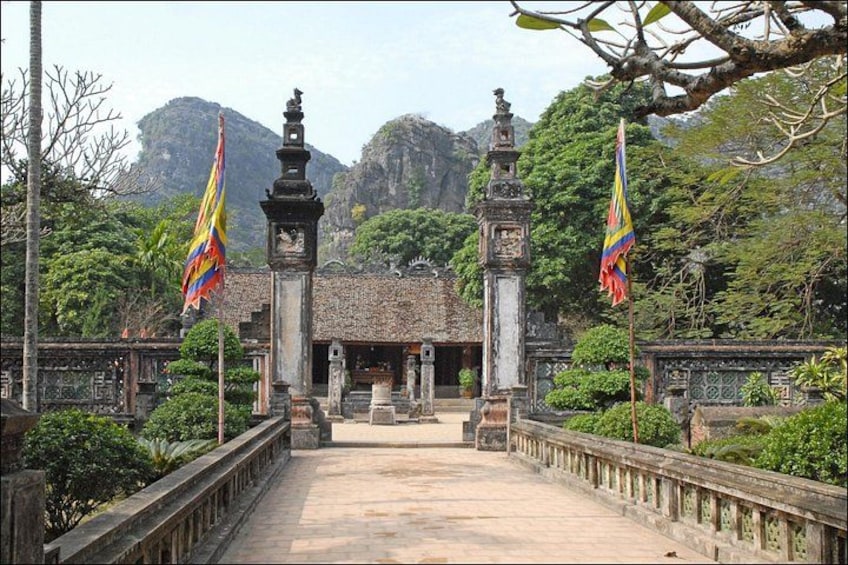 A temple entrance with two flagpoles, a stone pathway, and a mountain backdrop. 2