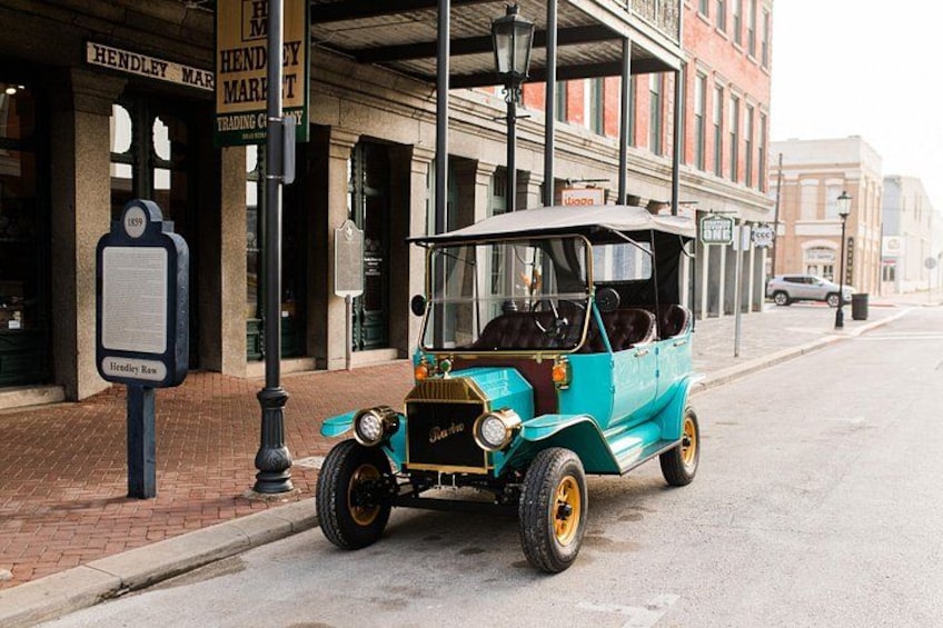 Un coche antiguo estacionado en una calle de la ciudad con edificios y un letrero que dice 'Hendley Market'. 5