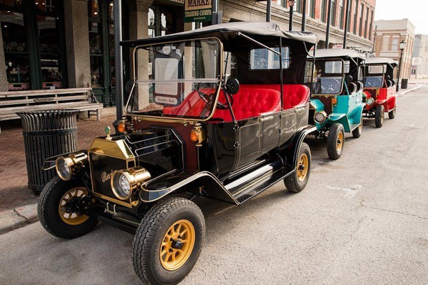 Un coche antiguo con carrocería negra y detalles dorados estacionado en una calle. 3