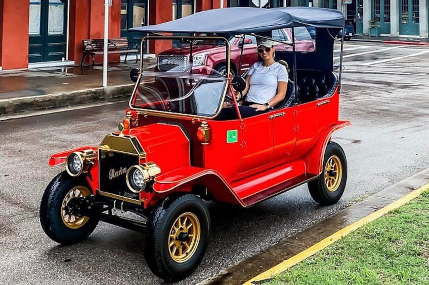 Un coche clásico rojo con detalles dorados estacionado en una calle. 2