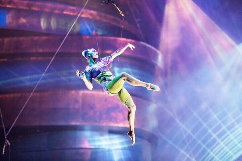 Un artista circense in aria, sospeso da corde, con uno sfondo colorato e astratto. 3