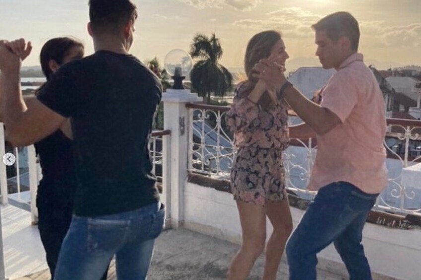 A couple dancing on a balcony with a scenic view of the sunset. 3