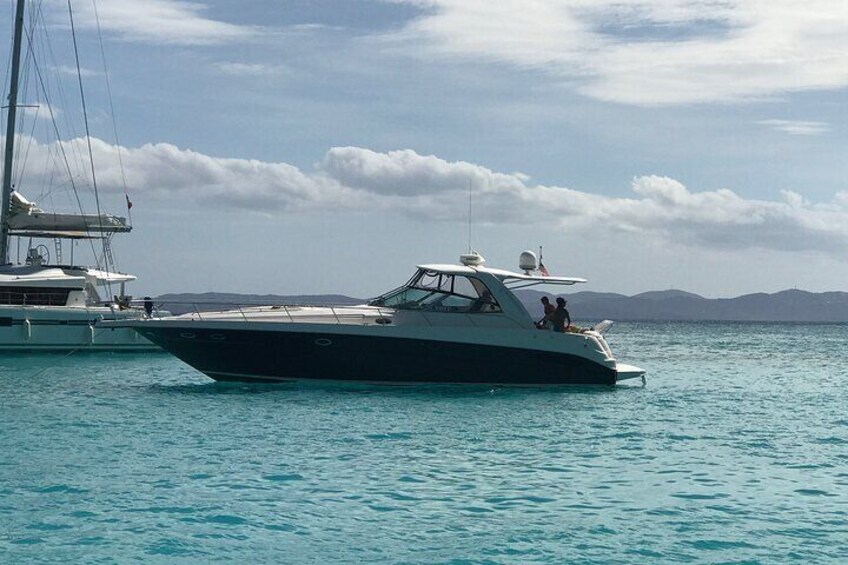 A black and white yacht on calm turquoise water with a clear sky and distant mountains. 4