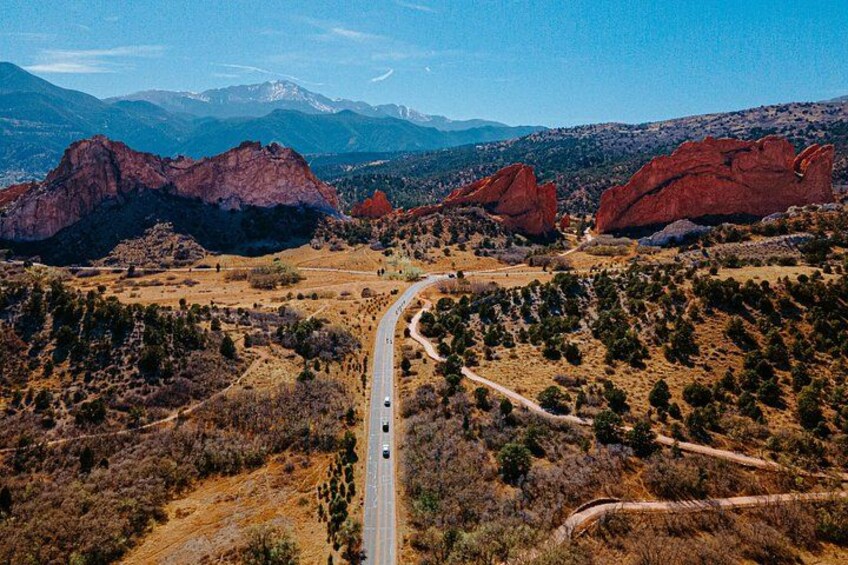 A winding road through a mountainous landscape with red rock formations and sparse vegetation. 2
