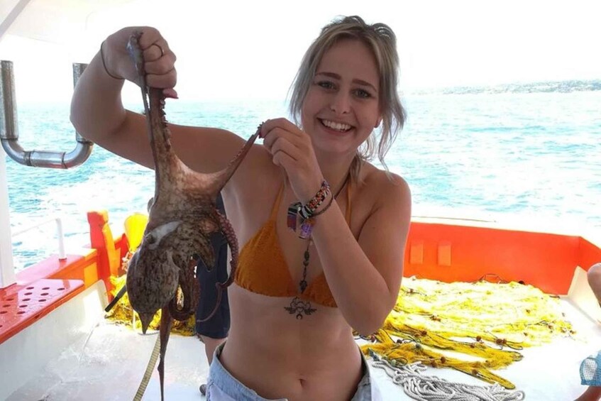 Una persona tiene in mano un pesce di grandi dimensioni su una barca, con una vista aperta sull'oceano. 1