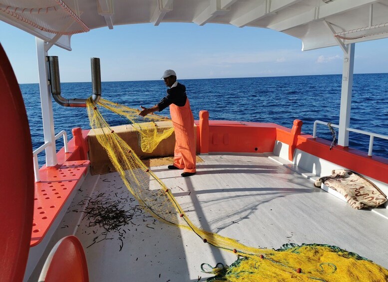 Una persona su una barca che maneggia reti da pesca. 2