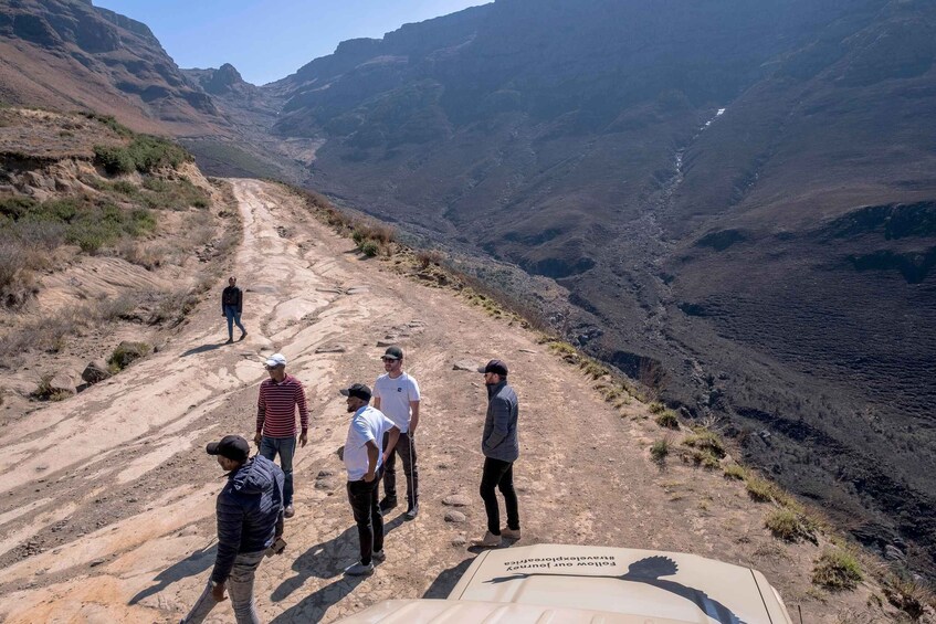 Un groupe de personnes se tient sur un sentier de terre dans un canyon aux parois rocheuses abruptes. 3