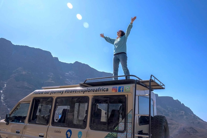 Une personne se tient debout dans un autobus, avec un paysage montagneux en arrière-plan. 5