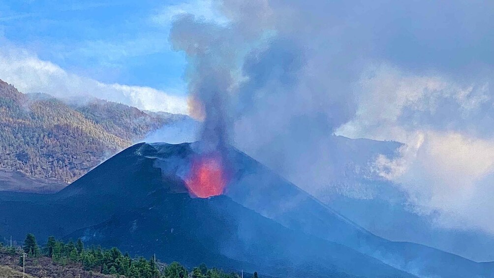 Un volcan rougeoyant, d’où s’échappent des panaches de fumée. 3
