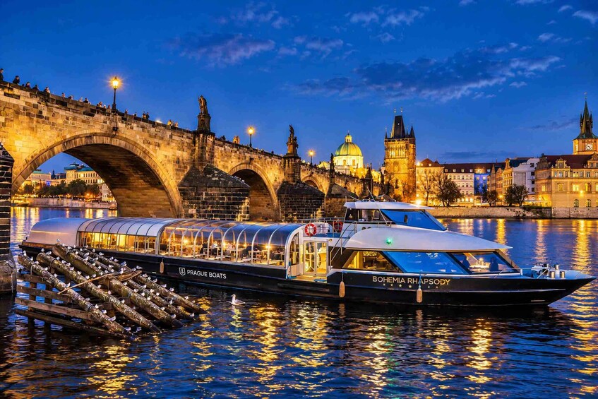 Un bateau fluvial baptisé « Prague Boats », doté d’un espace de restauration couvert, était amarré près d’un pont historique à arcades multiples. 1