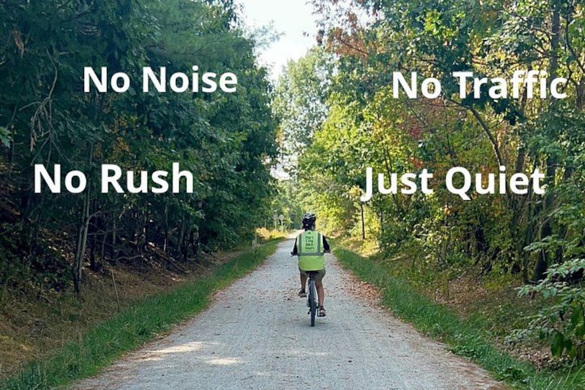 A person cycling on a quiet, tree-lined path with no traffic. 3