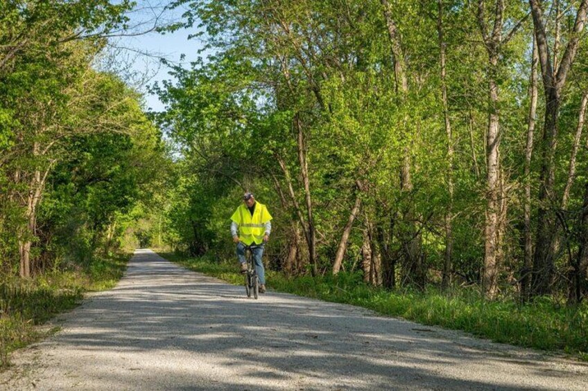 A cyclist on a paved road surrounded by dense green trees. 2