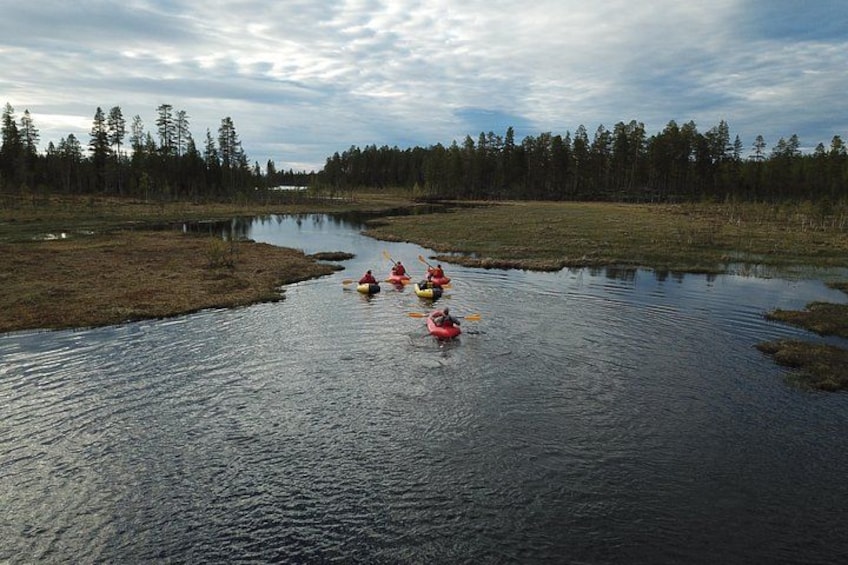 A group of kayakers on a calm river surrounded by a forest. 2