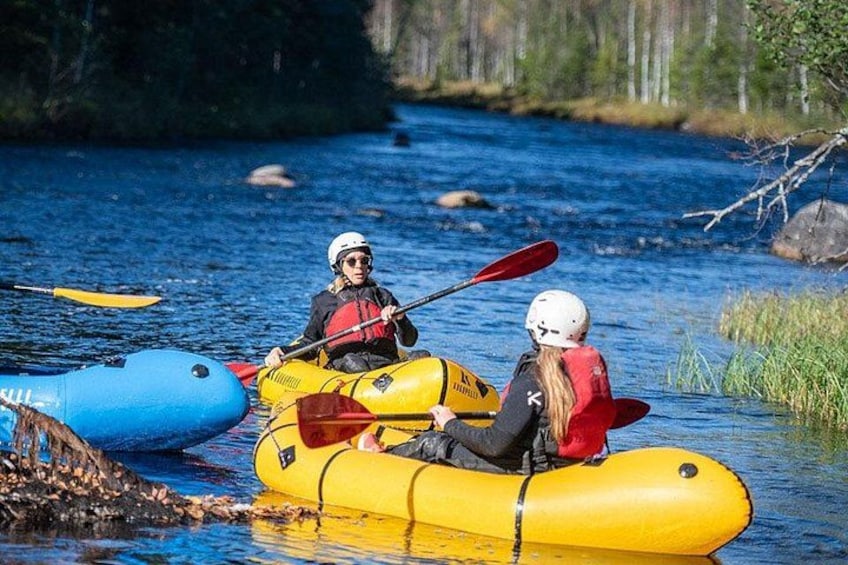 Two people kayaking on a river, wearing helmets and life jackets. 1