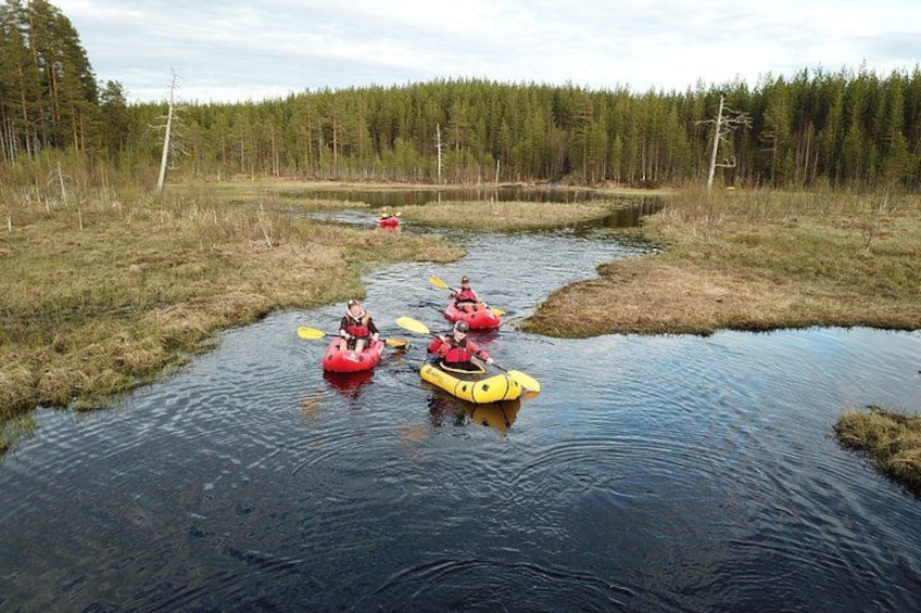 People kayaking on a calm river surrounded by a forest. 3