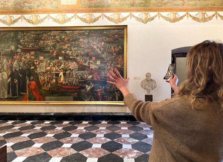 En person fotograferer et stort, historisk maleri i et kunstgalleri. 1