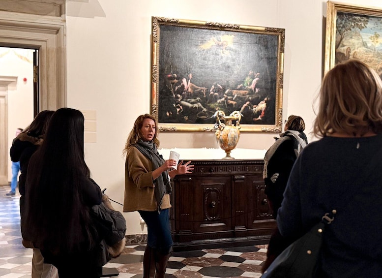 En person præsenterer i et galleri med et stort maleri og en vase på et bord. 2