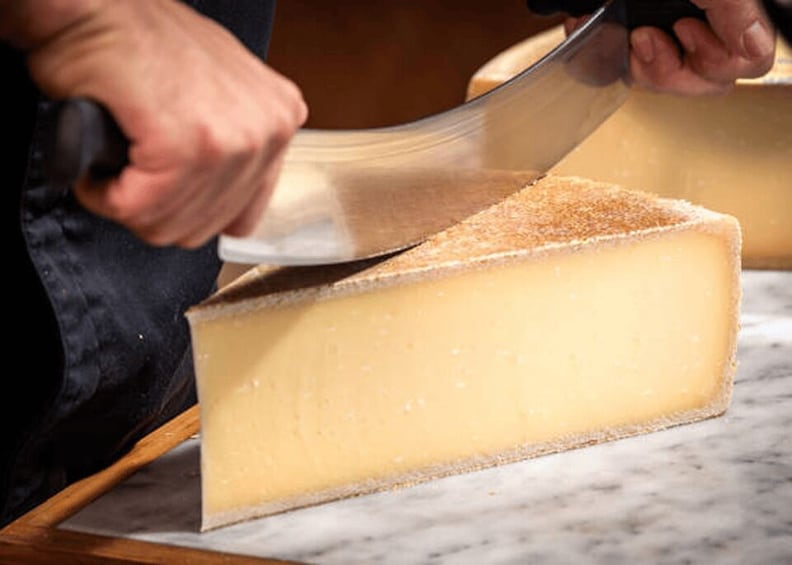 Une personne qui découpe une grosse portion de fromage à l’aide d’un couteau. 2