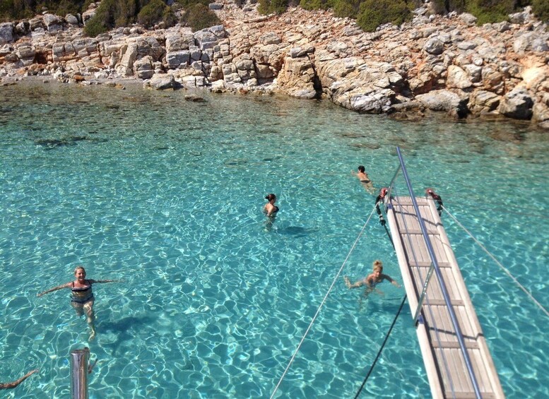 A clear blue pool with people swimming and a wooden dock extending into the water. 5